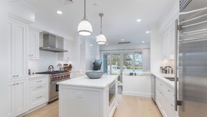 Una cocina moderna con armarios blancos, electrodomésticos de acero inoxidable e iluminación colgante.