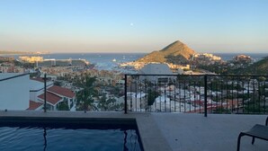 Un balcón con vistas a un pueblo costero, una montaña y el mar.