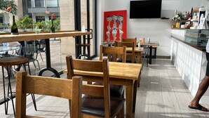 An indoor seating area with wooden chairs and tables, a flat-screen TV mounted on the wall, and a bar counter with various items. - Unwind in Style at your luxurious Retreat in the Heart of Cantonments (Accra)
