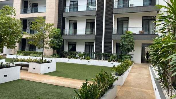 A modern multi-story building with balconies, a central courtyard with grass and plants, and a concrete pathway. - Unwind in Style at your luxurious Retreat in the Heart of Cantonments (Accra)