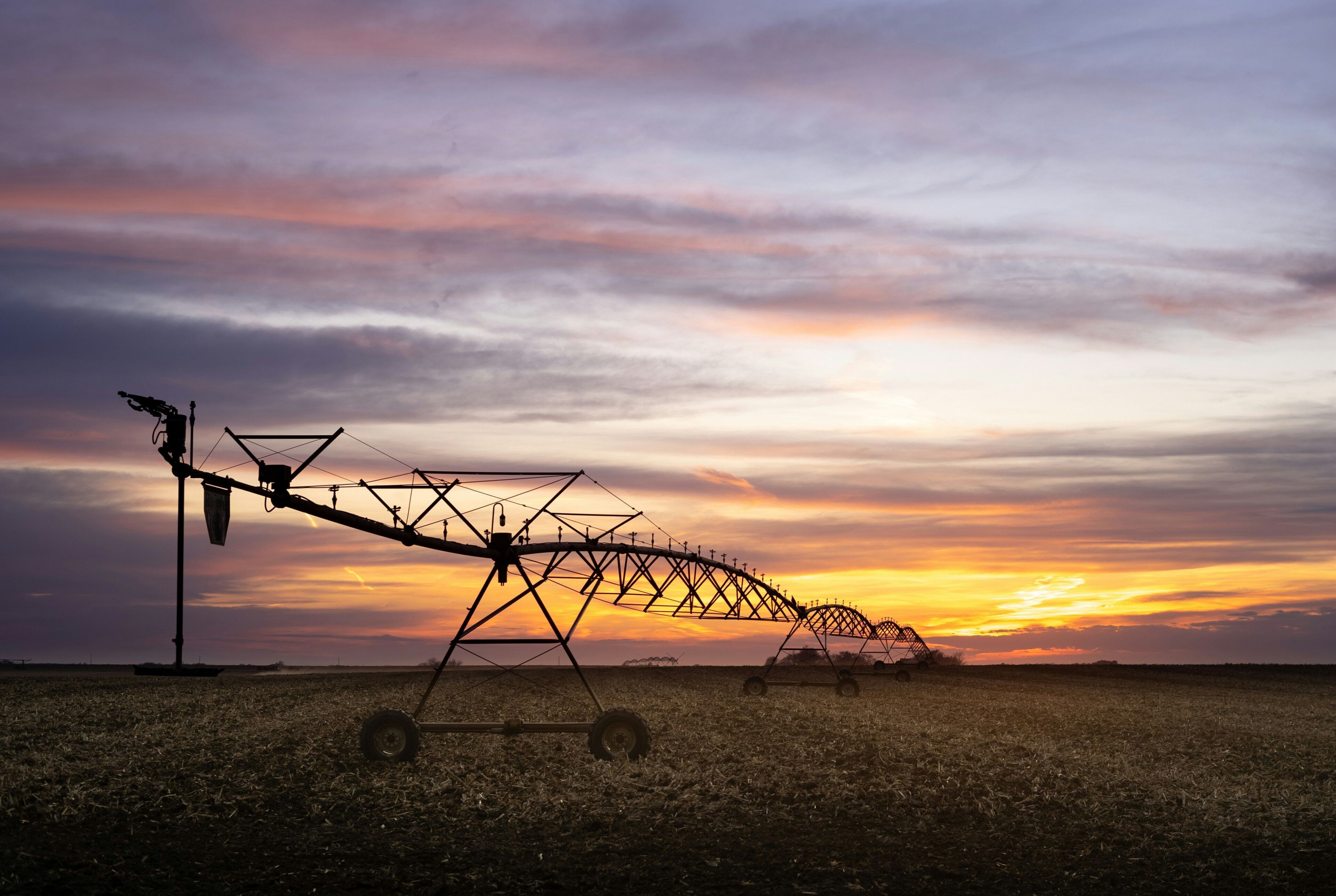 A field with agricultural machinery during sunset.