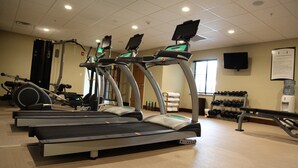 Ein Fitnessstudio mit Laufbändern, Kraftgeräten und Kurzhanteln.