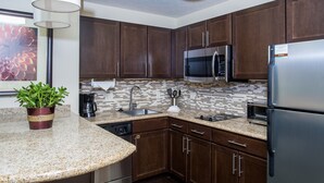 A modern kitchen with dark wooden cabinets, stainless steel appliances, a granite countertop, and a backsplash with a mosaic tile pattern. - King Suite, Breakfast, Pool, Near Univ of Nebraska (Lincoln)