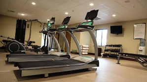 Un gimnasio con cintas de correr, máquinas de pesas y mancuernas.