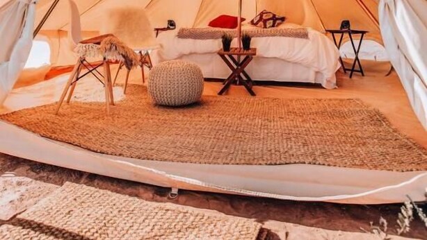A tent with a bed, pillows, a chair, and a small table. - Starlight Olympic (Port Angeles)
