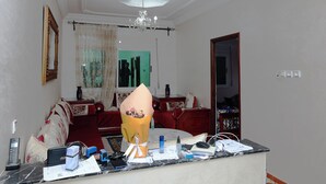 A hotel room with a bed, a desk with various items, a chandelier, and a red sofa. - MahdiAp (Chefchaouen)