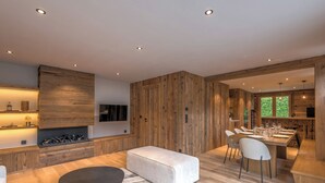 Un salon moderne doté d’une cheminée, de lambris en bois, d’un coin repas et d’une grande fenêtre.