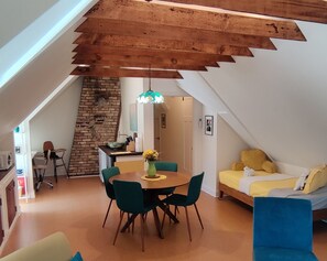 A dining area with a round table, chairs, and a hanging light fixture.