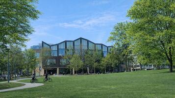 A modern building with large windows, surrounded by a grassy area and trees.