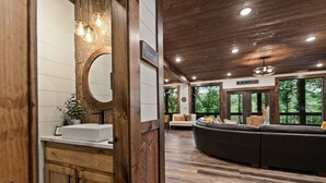 Ein modernes Interieur mit einem Holzlagerfläschchen, einem großen Spiegel und einer Sitzecke mit einem dunklen Sofa und einem Couchtisch.