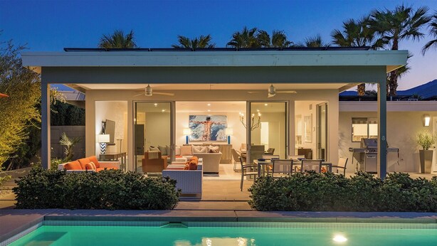 Una casa moderna con un espacio exterior cubierto, piscina y zona de comedor.