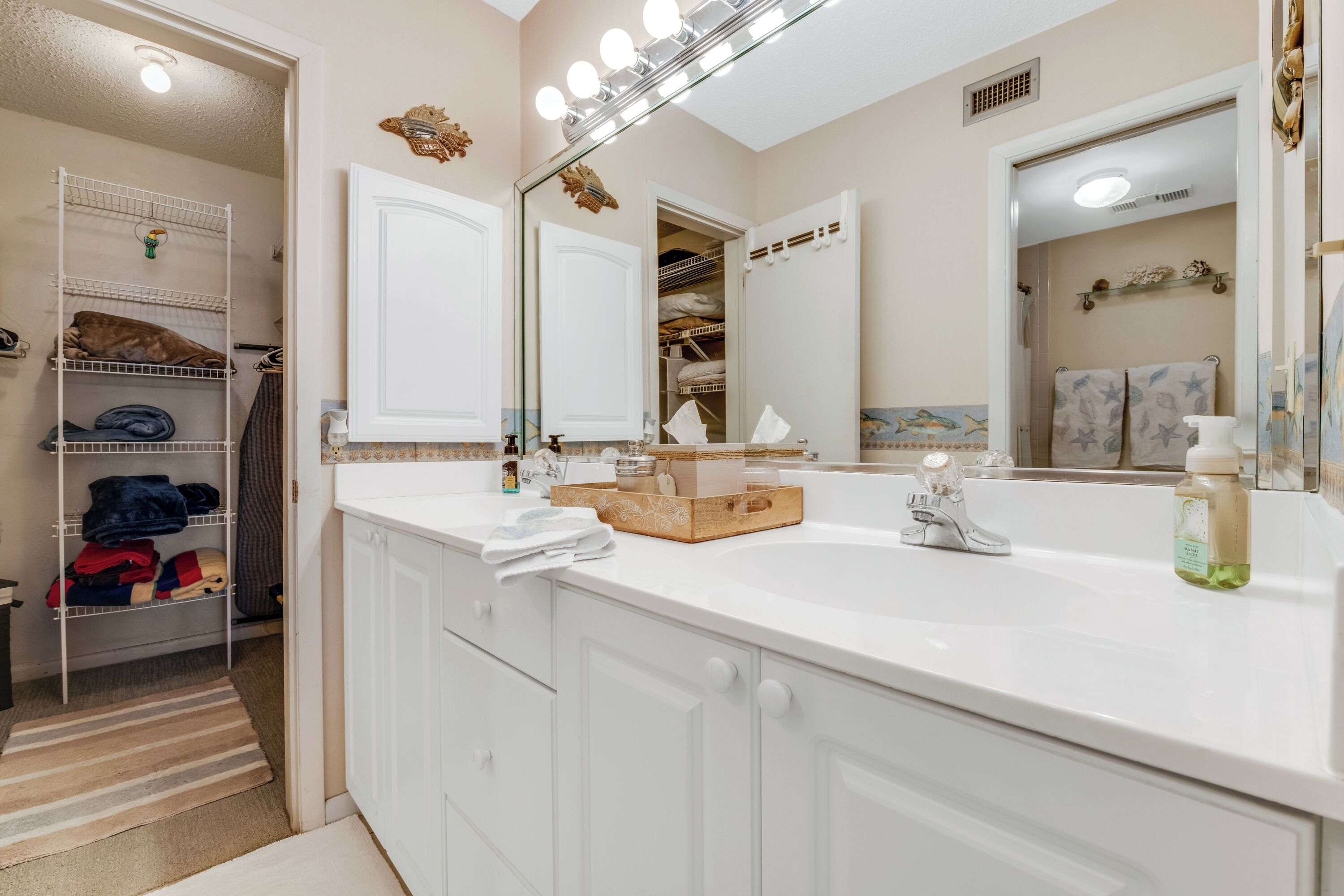A bathroom with a large mirror, vanity, and storage cabinets.