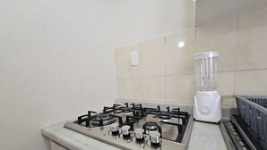 A kitchen with a gas stove, a blender, and a stainless steel sink. - Casa Flores (Tehuacán)