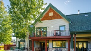 A two-story house with a balcony, stone foundation, and a covered patio area. - Thistlebrook Rendezvous,Decks off each bedroom!  Backyard & Views!!! (Steamboat Springs)