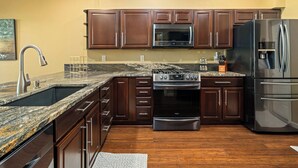 A kitchen with dark wooden cabinets, a stainless steel refrigerator, a built-in oven, and a granite countertop. - Thistlebrook Rendezvous,Decks off each bedroom!  Backyard & Views!!! (Steamboat Springs)