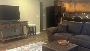 Un salon avec un canapé en cuir marron, un pouf assorti et un tapis à motifs.