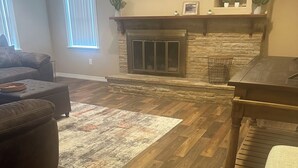 Un salon avec une cheminée, un plancher en bois, un canapé et une table basse.