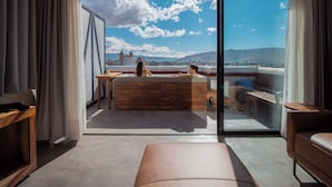 A modern room with a large window, a wooden bathtub, and a sofa. - Suites Amanecer by Casa del Sótano (Oaxaca)