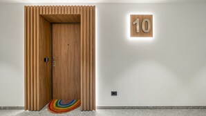 Una puerta de madera con un letrero con el número 10 arriba, una alfombra pequeña y una pared lisa.