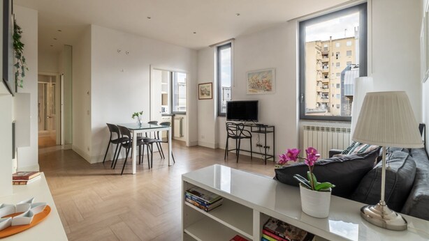 A modern living room with a dining area, a television, and a sofa. - GuestHost - Modern and bright apartment of 60 sqm, able to accommodate up to 2 people, located on the second floor of a building without a lift (NOT suitable for disabled people).The property is located in an area well connected by public transport, just (Roma)