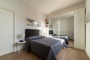 A bedroom with a bed, bedside tables, a mirror, and artwork on the wall.