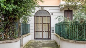 Una entrada protegida por un muro con dos puertas, un pequeño alero encima de la puerta y el número '1' en la pared a la derecha.