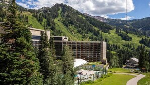 A hotel with a modern design, surrounded by lush green hills and mountains. - 2BR Cliff Club Retreat – Ski-In/Ski-Out! (Sandy)