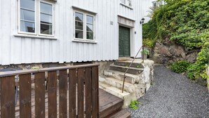 Un bâtiment blanc doté d’une terrasse en bois, d’un escalier en pierre et d’un chemin de gravier.