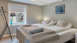 Une chambre à coucher avec un lit, une fenêtre, un tableau et un trépied.