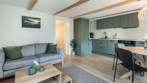 Un salon moderne avec un canapé gris, une table basse en bois et un coin repas comprenant une table et des chaises.