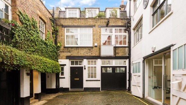 A narrow alleyway with a row of traditional brick buildings, each with a black door and white-framed windows. - Oxford Circus Apartments (London)