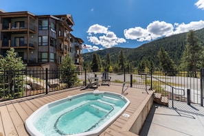 A wooden deck with a hot tub, a fenced area, and a mountain backdrop. - Cl1302k-2 (Keystone)
