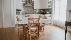 A kitchen with white cabinets, a marble countertop, and a dining table with chairs. - Dimora Adriani on the Noble Floor, Charm & Relax in the Heart of Langhe (Cherasco)