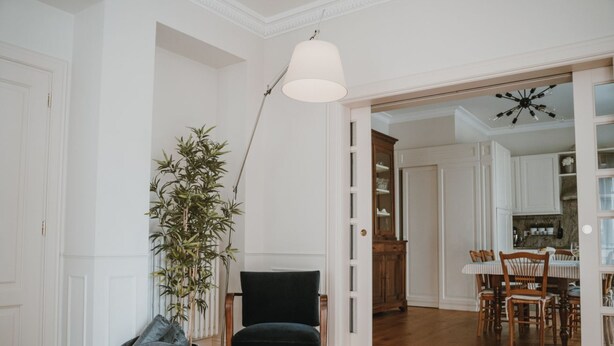 A room with a wooden floor, a dark chair, a lamp, a plant, and a dining area with a table and chairs. - Dimora Adriani on the Noble Floor, Charm & Relax in the Heart of Langhe (Cherasco)