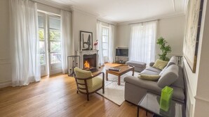 A living room with a fireplace, a sofa, a coffee table, and a television. - Dimora Adriani on the Noble Floor, Charm & Relax in the Heart of Langhe (Cherasco)