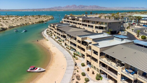 A hotel with multiple floors, a beachside location, and a view of the water and mountains in the background. - Amazing Remodeled Lake Havasu Condo / Kingsview - steps from the London Bridge! (Lake Havasu City)