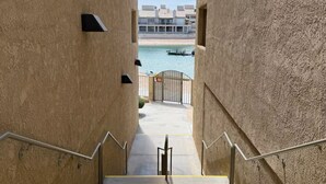 A concrete staircase with metal railings leading to a gated area with a view of a body of water and buildings in the distance. - Amazing Remodeled Lake Havasu Condo / Kingsview - steps from the London Bridge! (Lake Havasu City)