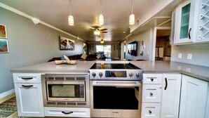 A kitchen with white cabinets, a Bosch oven, a microwave, and a stove. - Amazing Remodeled Lake Havasu Condo / Kingsview - steps from the London Bridge! (Lake Havasu City)