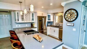 A modern kitchen with white cabinets, stainless steel appliances, and a central island. - Amazing Remodeled Lake Havasu Condo / Kingsview - steps from the London Bridge! (Lake Havasu City)