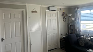 A room with white doors, a welcome sign, a ceiling fan, a bookshelf, and a window with curtains. - Chalet for Hire in Florida Hemsby (Great Yarmouth)