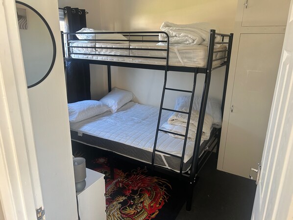 A bunk bed with white bedding and a ladder, a wardrobe, and a dragon mural on the floor. - Chalet for Hire in Florida Hemsby (Great Yarmouth)