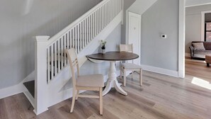 Un escalier avec des rampes blanches menant à un palier où se trouvent une table ronde et deux chaises.