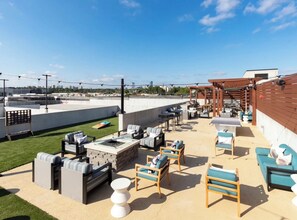 Relax and socialize in style on this rooftop terrace with city views, sofas, chairs, and a fire pit.