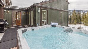 A hot tub outside a wooden building with a view of snow-covered mountains. - Luxury 7 Bedroom Home + Hot Tub + Views of Lone Peak (Big Sky)