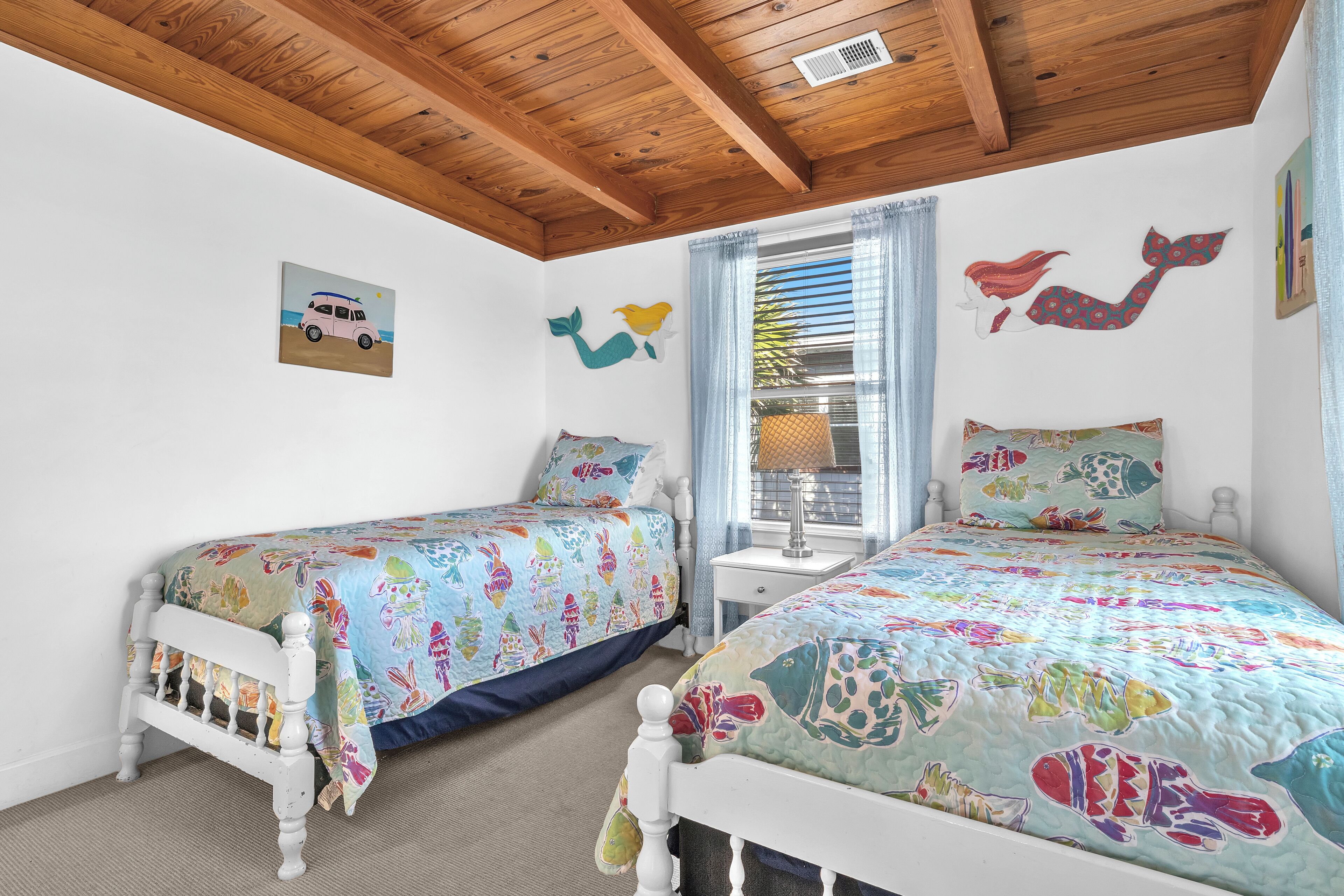 Une chambre avec deux lits, un plafond en bois et une fenêtre avec des rideaux.
