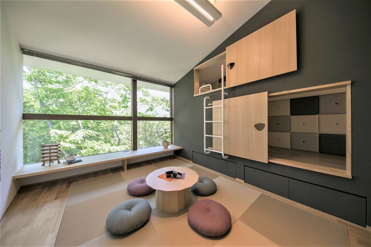 Una habitación moderna con un ventanal grande, asientos integrados y un mueble de pared.