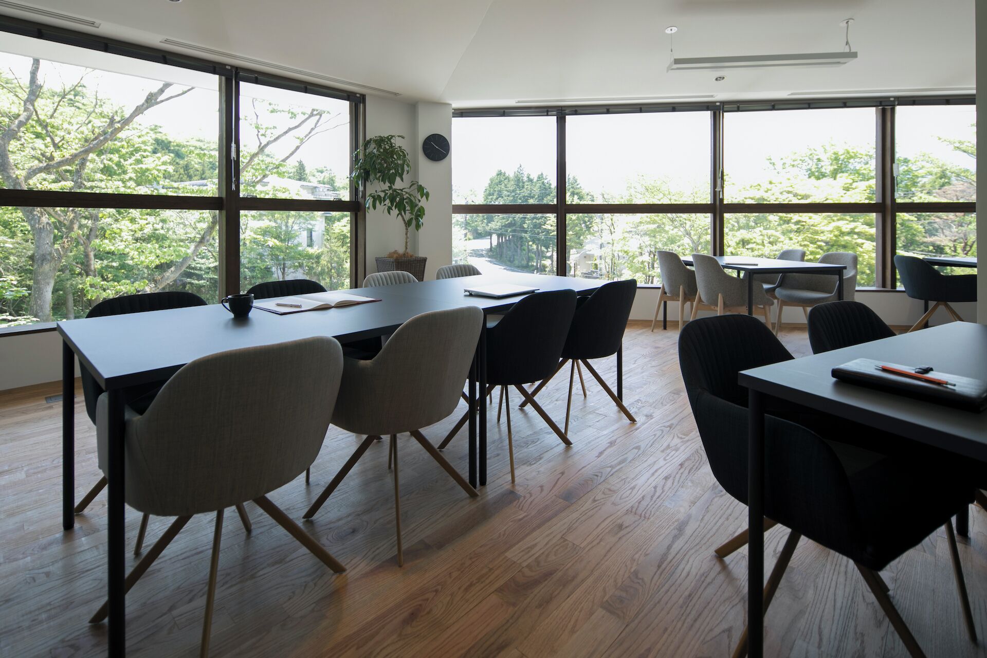 A spacious conference room with large windows, wooden flooring, and modern furniture.