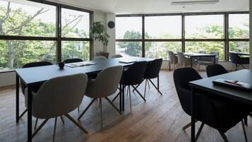 A spacious conference room with large windows, wooden flooring, and modern furniture.