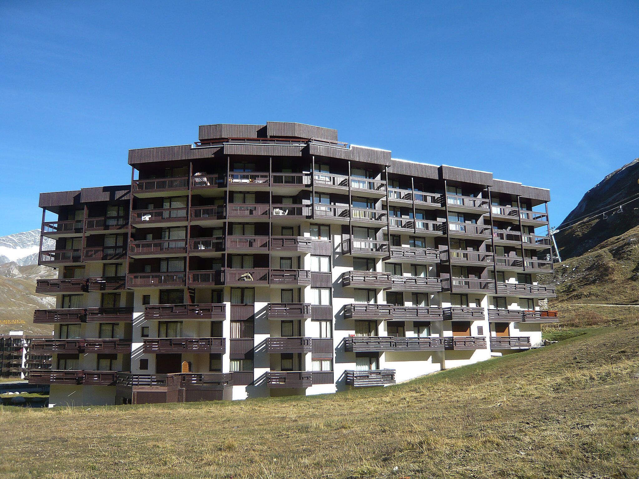 Ett hotell med flera våningar, balkonger och en bergig bakgrund.