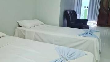 Quarto de hotel com duas camas de solteiro, uma cadeira e um guarda-roupa.